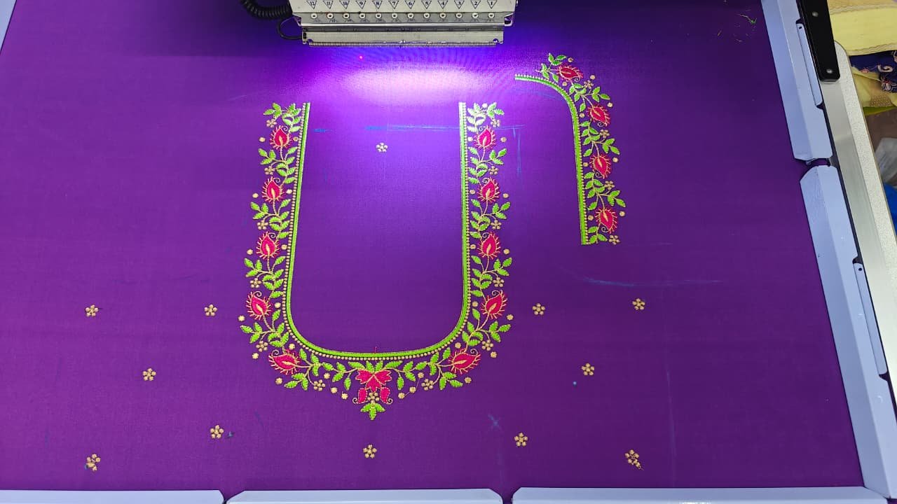 Floral vine neckline embroidery being stitched on purple fabric
